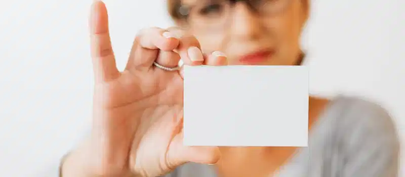 Close-up of a woman holding a blank business card with a blurred background for copyspace.