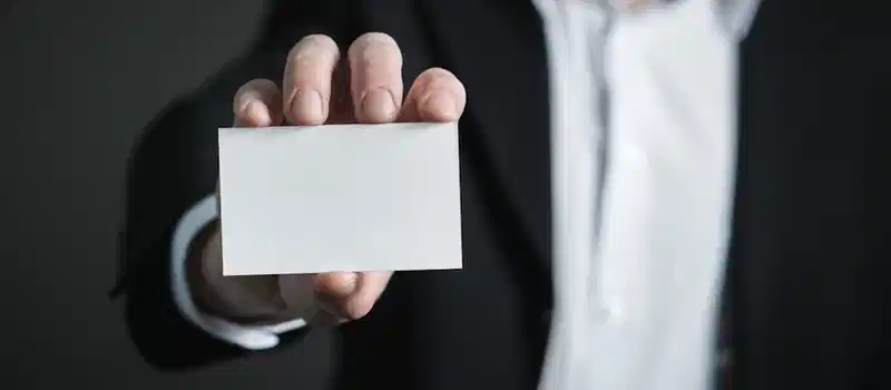 A man in a suit presenting a blank business card for corporate usage.