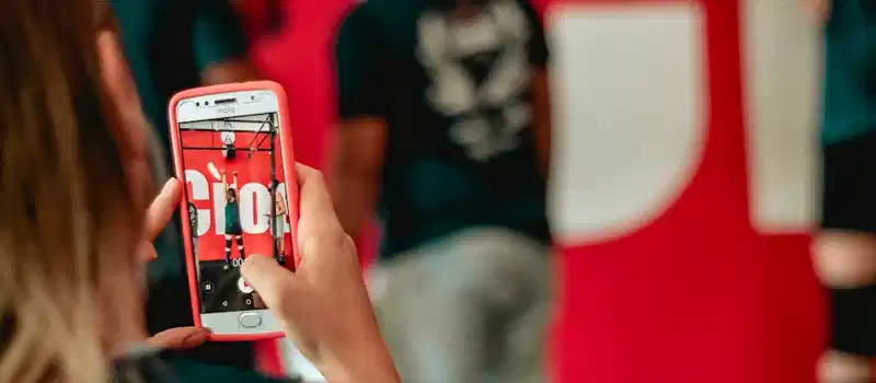 A woman captures a moment at an event on her smartphone indoors.