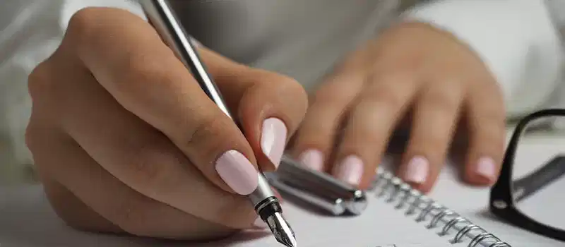 A detailed image of handwriting in a notebook with a fountain pen and glasses, ideal for office themes.