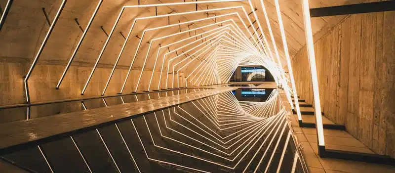 Explore a modern tunnel with geometric LED light patterns reflecting on the water.