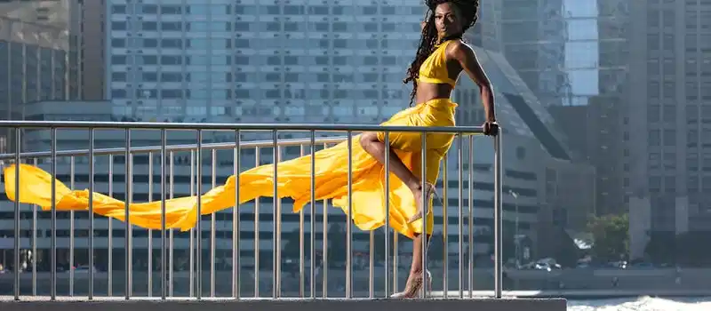 Stunning fashion model in flowing yellow dress with Chicago skyline backdrop.