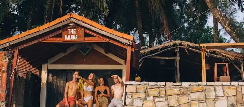 Group of friends relaxing at a beach bar on a sunny day, capturing carefree summer vibes.