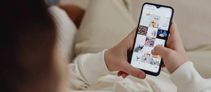 Person using smartphone to browse Instagram indoors, showing social media engagement.