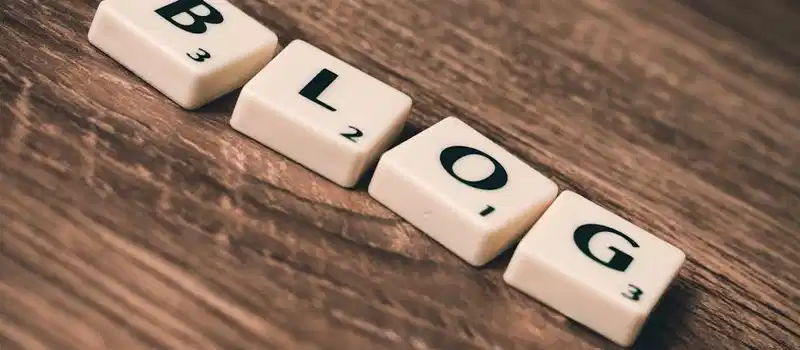Scrabble tiles spelling 'BLOG' on a wooden background, symbolizing creativity and writing.