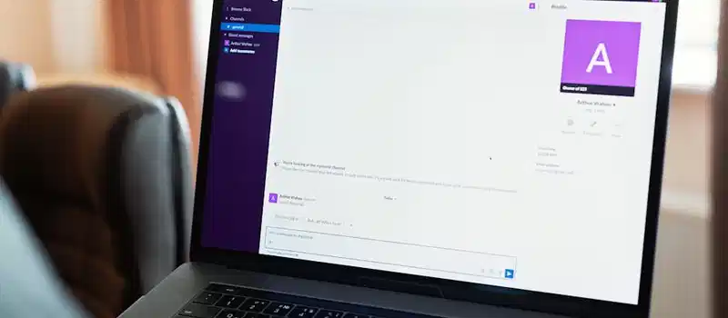 Person using a laptop with an online communication platform, showcasing modern work tech.