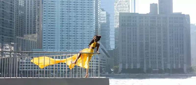 Model in a flowing yellow dress posing by the Chicago River with a stunning skyline backdrop.