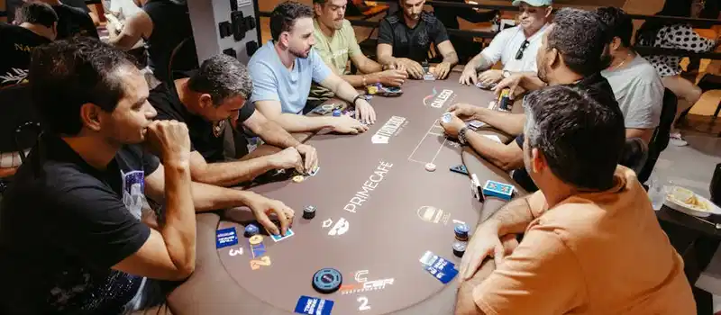 Group of adults playing poker at a Prime Café table, showcasing strategy and focus.