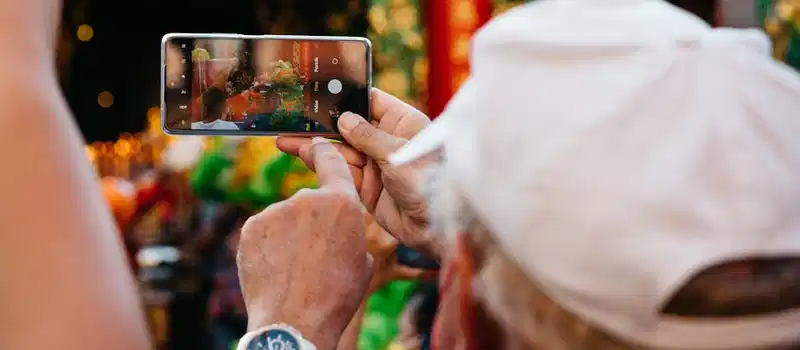A person captures a vibrant street event with a smartphone, focusing on details and colors.