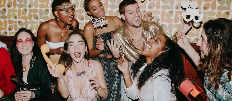 A diverse group of friends joyfully celebrating New Year's Eve indoors, capturing festive fun.