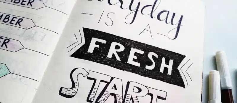 Notebook page featuring motivational quote 'Everyday is a fresh start' with colorful pens.