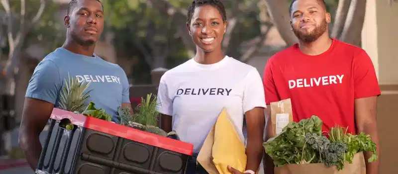 Diverse group delivering groceries and packages outdoors. Smiling and professional.