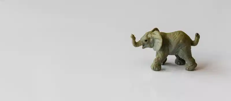 Tiny elephant figurine in side view on a plain white background, perfect for art and wildlife themes.