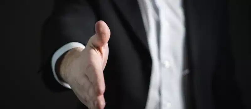 Close-up of a businessman extending hand for a handshake, symbolizing agreement and partnership.