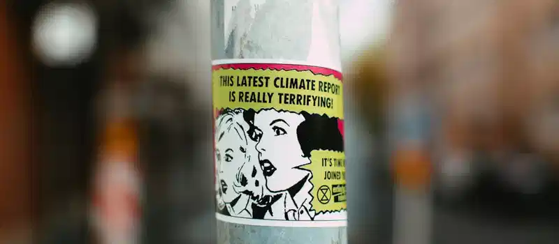 Sticker on pole with comic-style graphics raising awareness about climate change.