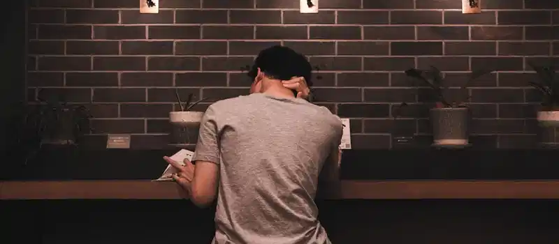 A man relaxes and reads in a stylish cafe, featuring modern decor and soft lighting.