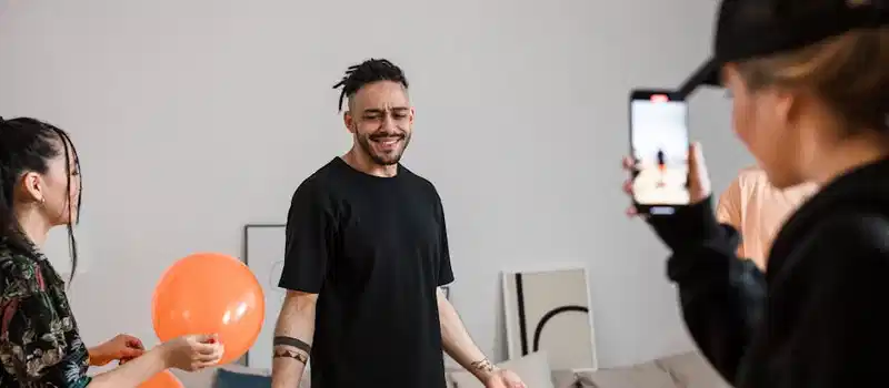 A group of friends filming a playful TikTok dance video indoors, capturing joy and creativity.