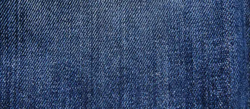 Textured blue denim fabric with detailed weaving visible in close-up macro view.