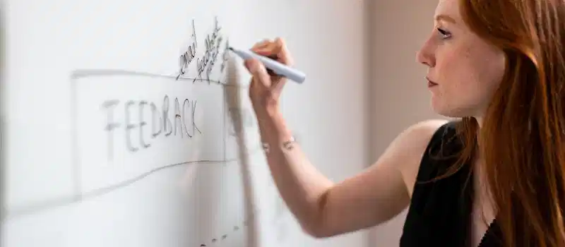 Focused woman writing on a whiteboard during a business planning session.