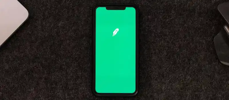 Smartphone displaying trading app on a desk for stock finance concepts.