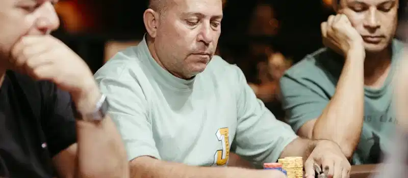 Group of adult men focused on a poker game at a casino table.