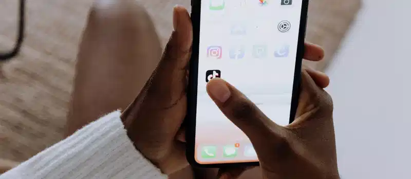 Close-up of hands with a smartphone using the TikTok app indoors, reflecting modern mobile technology.