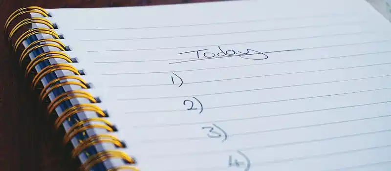 A close-up view of a handwritten to-do list on a spiral notebook with numbers for tasks.