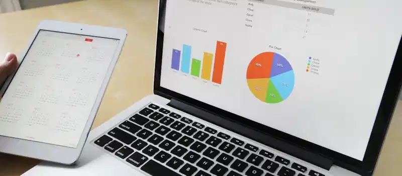 Laptop displaying charts and graphs with tablet calendar for data analysis and planning.