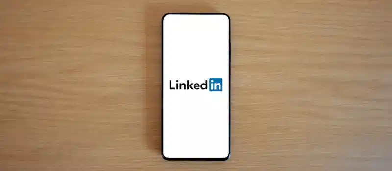 Top view of a smartphone displaying the LinkedIn logo on a wooden surface.