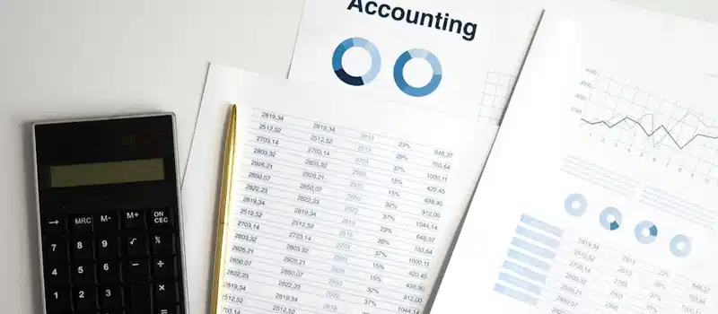Calculator and accounting documents with charts on a workspace.