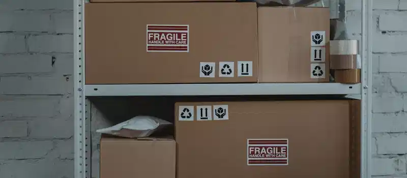 Cardboard boxes labeled 'Fragile' stacked on metal shelving in a storage room.