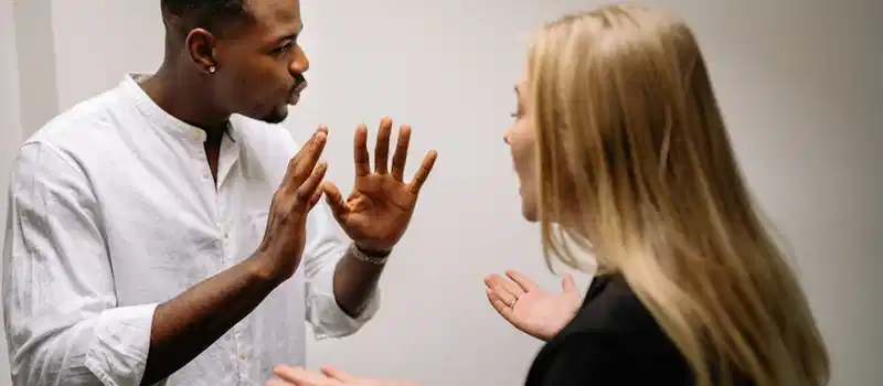 Frustrated coworkers in heated discussion, expressing disagreement in office setting.