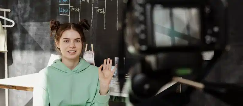 Woman in a mint green hoodie streaming from a home studio setup.