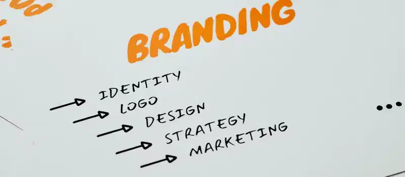 Close-up of a paper with branding, identity, design, strategy, and marketing concepts in orange and black.