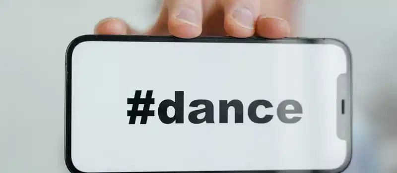 Close-up of a phone screen displaying the #dance hashtag, held by an adult.