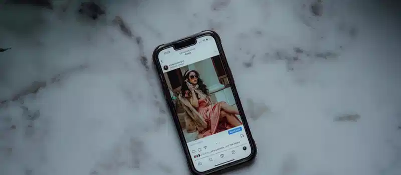 A smartphone showing an Instagram post against a marble background, showcasing modern social media use.