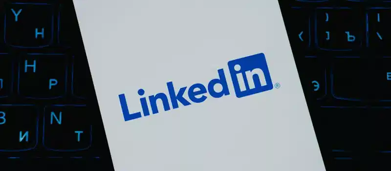 Close-up of LinkedIn logo on smartphone screen, with keyboard background.