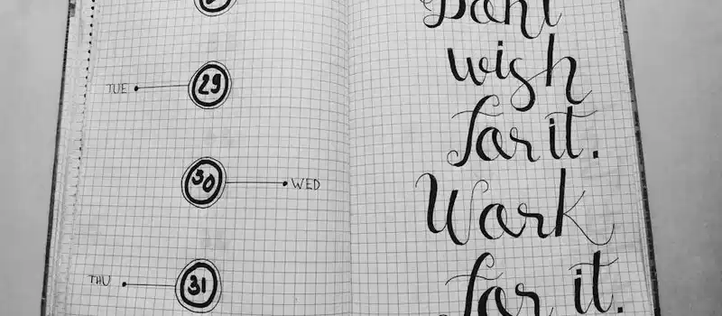 Open planner notebook with motivational quote in artistic handwriting. Organized layout, perfect for goal setting.