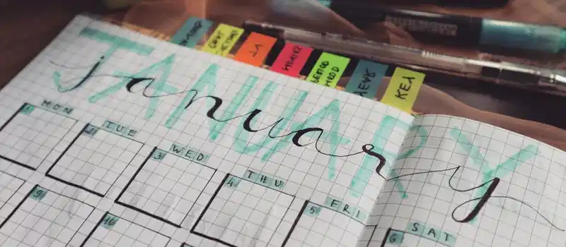 Handwritten January planner page with tags and pens on a desk. Perfect for organizing schedules.