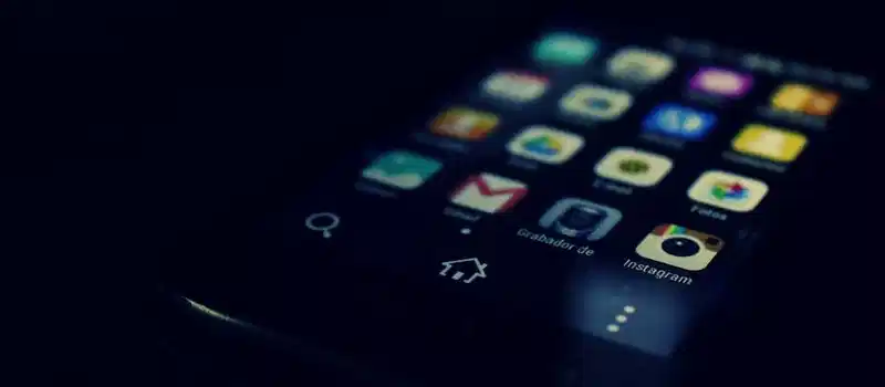 Dark-themed close-up of a smartphone screen highlighting various apps and touchscreen technology.