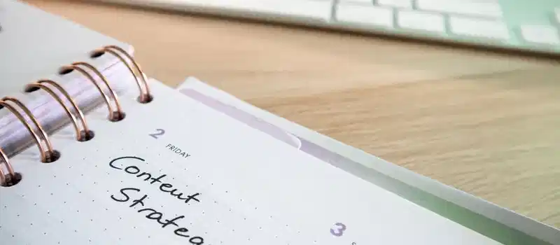Content strategy written in planner with keyboard on wooden desk